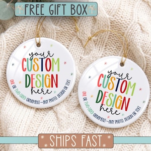 May include: Two round white ceramic ornaments with gold hanging strings. The text reads: your CUSTOM DESIGN here, ONE OR TWO-SIDED ORNAMENT~ANY PHOTO, DESIGN OR TEXT. Small colorful starburst accents surround the text in red, green, blue, and yellow.