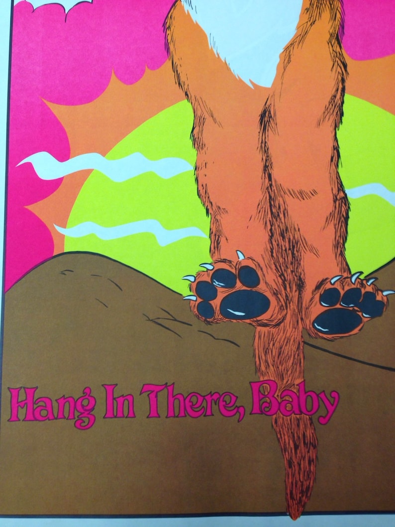 Op de afbeelding: Een vintage poster met een cartoonvos met oranje vacht, zwarte poten en een witte borst. De vos hangt ondersteboven tegen een roze lucht, gele zon en bruine grond. De tekst "Hang In There, Baby" is roze.
