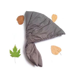 May include: A charcoal gray quilted head scarf with a smooth, padded texture and a triangular shape that tapers into two long, tied ends. The fabric has a subtle sheen, and the design features stitched seams that create a soft, puffy appearance.