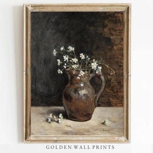 Könnte beinhalten: Gerahmtes Vintage-Stillleben-Gemälde mit einem braunen Krug, gefüllt mit weißen Blumen. Das Kunstwerk hat einen dunklen Hintergrund und eine hellfarbige Oberfläche. Der Rahmen ist goldfarben, und der Text "GOLDEN WALL PRINTS" befindet sich unten.