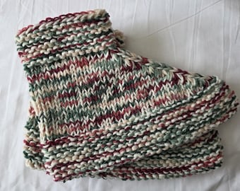 May include: Hand-knitted slipper socks in a mix of colors including burgundy, green, cream, and black. The socks are folded over, showing the thick, textured knit. The background is a white, wrinkled fabric.