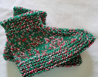 May include: A pair of knitted slipper socks in a festive color scheme. The socks feature a mix of green, red, and white yarn, creating a textured pattern. The cuff is folded over, and the socks appear soft and warm.
