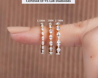 May include: Three gold eternity bands featuring marquise-cut, certified EF-VS lab diamonds. The rings are labeled with widths of 1.5mm, 2mm, and 2.5mm, showcasing the varying sizes of the stones set in a continuous row along each thin metal band.