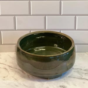 May include: A handmade, wooden serving tray with a natural finish. The tray features a rectangular shape with raised edges and integrated handles. The wood grain is visible, showcasing the tray's rustic charm. Dimensions are approximately 16 inches long, 10 inches wide, and 2 inches deep.