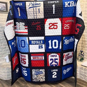 May include: A patchwork quilt constructed from various sports jerseys featuring team names like Royals, Dodgers, and South Lex, along with player names such as Cooper and Landon, and jersey numbers including 1, 2, 10, and 25 in a grid pattern.