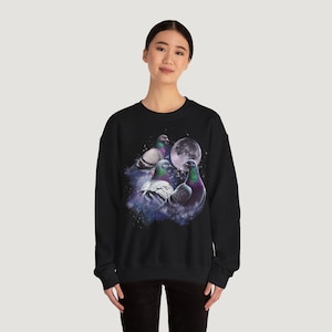 Könnte beinhalten: Schwarzes Sweatshirt mit einer Grafik von drei Tauben mit schillernden Hälsen, vor dem Hintergrund eines Vollmonds und eines sternenklaren, nebligen Himmels. Das Design ist mittig auf der Brust platziert.