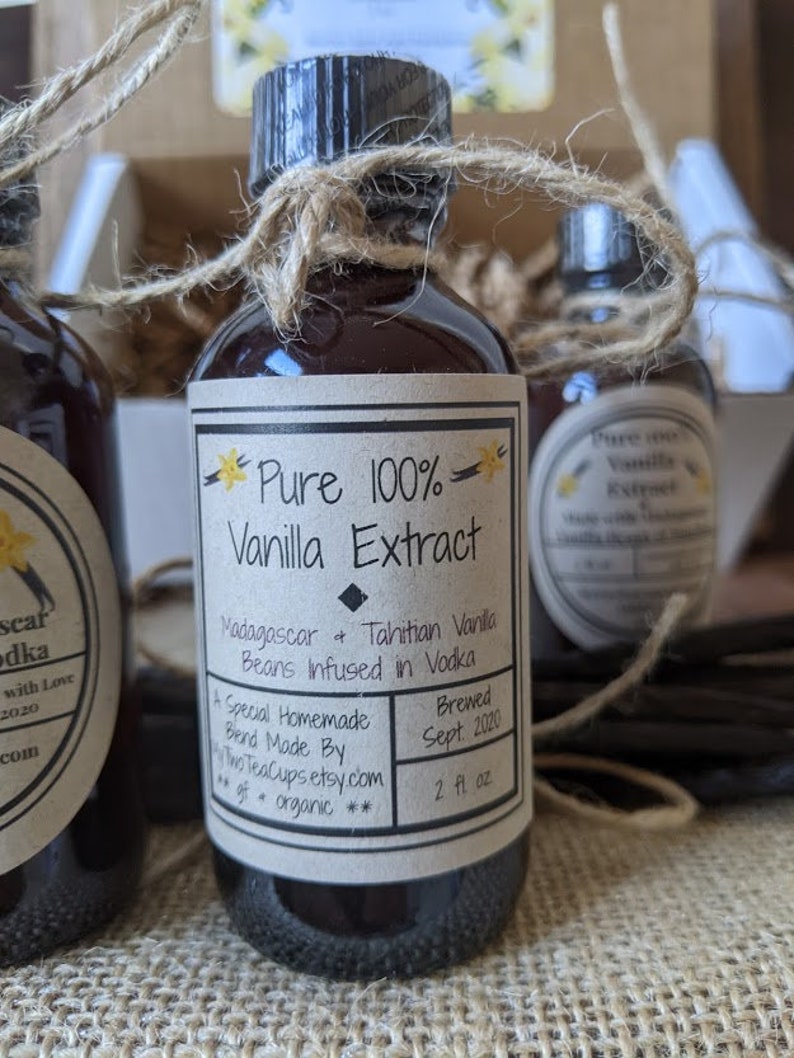 May include: A glass bottle of pure vanilla extract with a brown label that reads "Pure 100% Vanilla Extract" and "Madagascar & Tahitian Vanilla Beans Infused in Vodka". The label also includes the text "Brewed Sept 2020" and "2 fl oz".
