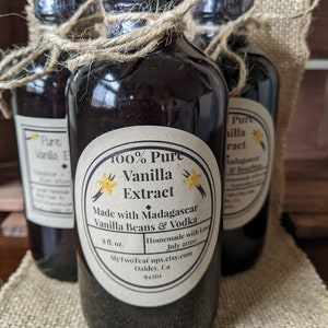 May include: Three glass bottles of 100% pure vanilla extract made with Madagascar vanilla beans and vodka. The bottles are tied with twine and have labels with the text "100% Pure Vanilla Extract", "Made with Madagascar Vanilla Beans & Vodka", "Homemade with Love July 2020", "MyTwoTeaCups.etsy.com", "Oakley, Ca 94561".