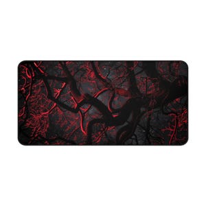 May include: A rectangular desk mat with a dark forest design. The image shows black tree branches with bright red accents against a dark grey backdrop. The mat has rounded corners.