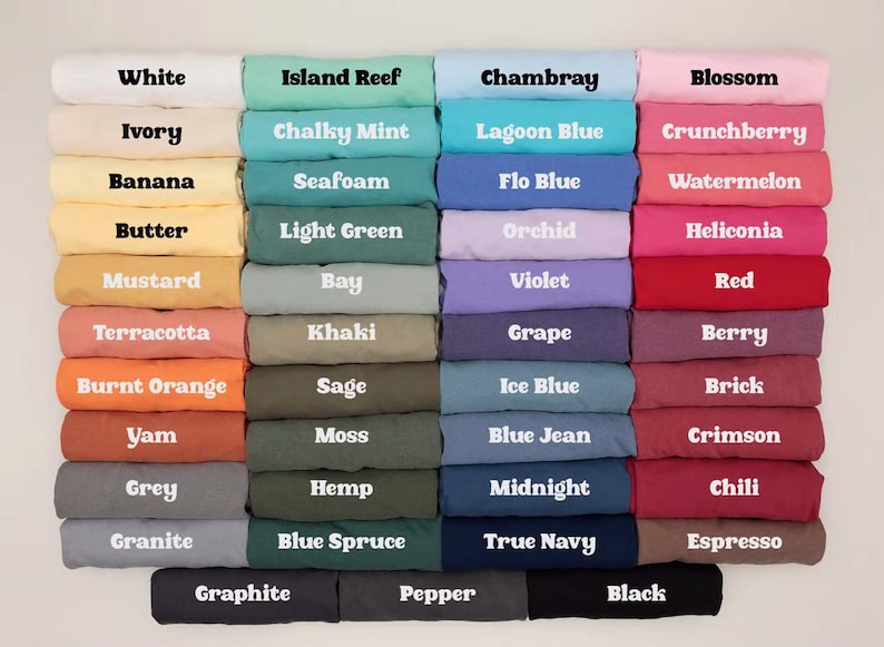 Puede incluir: Una carta de colores con cuarenta y ocho camisetas dobladas dispuestas en una cuadr&iacute;cula. Cada camiseta muestra el nombre de su color en texto negrita blanco o negro. La paleta incluye varios tonos de blanco, amarillo, naranja, verde, azul, morado, rosa, rojo, marr&oacute;n, gris y negro.