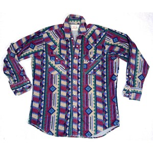 Puede incluir: Camisa de manga larga con un estampado geométrico del suroeste en tonos borgoña, verde azulado, beige y azul. Tiene dos bolsillos en el pecho y cierres de botón a presión de perlas. El cuello es de estilo clásico.