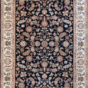 May include: A rectangular area rug with a navy blue field, featuring a dense floral pattern in shades of beige, brown, and red. The rug has a cream-colored border with intricate floral and geometric designs. The rug's edges are finished with a dark blue border and fringe.