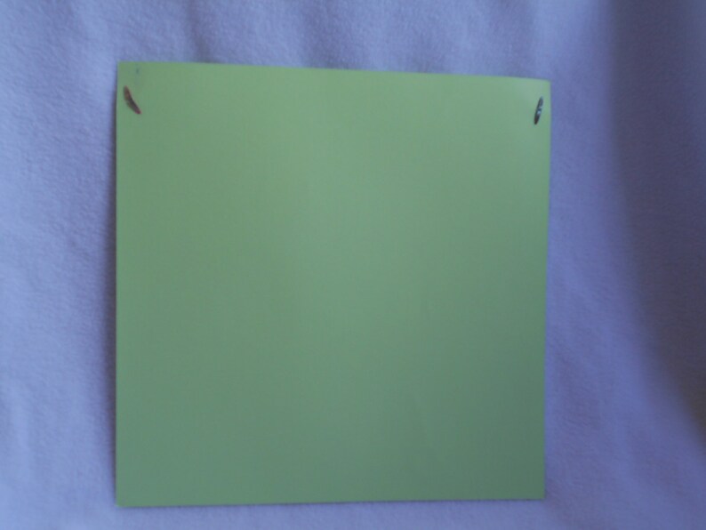 May include: A light green sheet of paper with two small holes in the top right and left corners.
