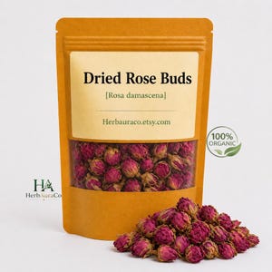 Könnte beinhalten: Eine braune Packung getrockneter Rosenknospen, beschriftet mit "Dried Rose Buds [Rosa damascena]" mit der Website Herbauraco.etsy.com. Die Packung hat ein klares Fenster, das die rosa Knospen zeigt. Ein kleiner Haufen Knospen liegt vor der Packung. Die Packung ist mit "100% Organic" gekennzeichnet.