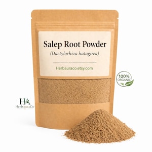 May include: A brown paper bag filled with Salep Root Powder (Dactylorhiza hatagirea). The bag has a white label with the product name and website address. A small pile of the powder sits in front of the bag. A green leaf logo indicates the product is 100% organic.
