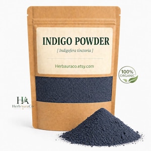 Peut inclure: Un sachet en papier brun avec l'inscription "INDIGO POWDER" et le nom botanique. Il contient de la poudre bleu foncé, avec un petit tas devant. Un autocollant "100% ORGANIC" est également visible.