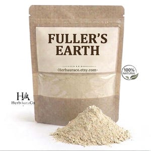May include: A brown paper bag with a clear window containing Fuller's Earth powder. The bag has the text "FULLER'S EARTH" and "100% NATURAL" printed on it. A small pile of the powder sits in front of the bag.