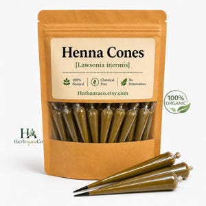 Może przedstawiać: Brązowa papierowa torebka wypełniona ciemnozielonymi rożkami z henną. Etykieta zawiera napisy Henna Cones, Lawsonia inermis, 100% Natural, Chemical Free, No Preservatives oraz Herbauraco.etsy.com. Po prawej stronie widoczne jest logo 100% Organic.