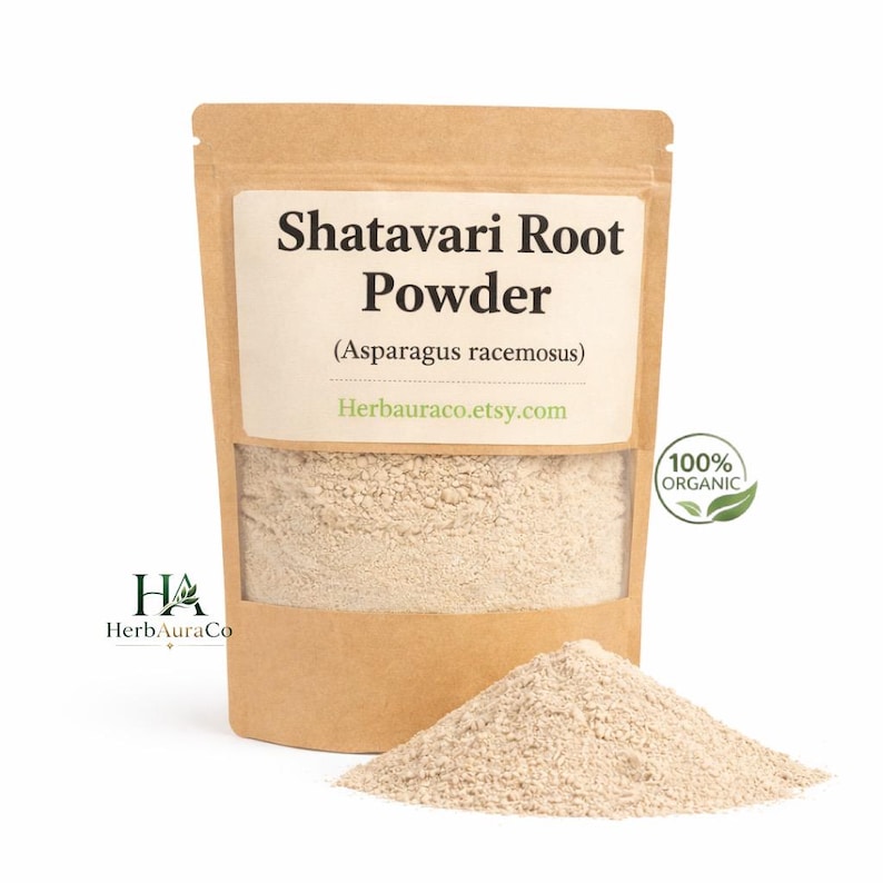May include: A kraft paper bag of Shatavari Root Powder, with a clear window showing the light beige powder inside. The label reads "Shatavari Root Powder (Asparagus racemosus)" and "100% Organic". A small pile of powder sits in front of the bag.