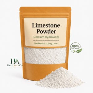 May include: A tan stand-up pouch containing white limestone powder, labeled Calcium Hydroxide and herbauraco.etsy.com, with a 100% organic seal. A small pile of the fine white powder sits in front of the pouch, which features the HerbAuraCo logo.