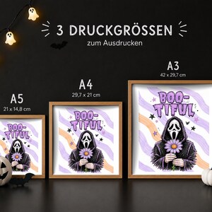 以下が含まれることがあります： A5、A4、A3サイズの額入りプリント3枚。それぞれ、デイジーの花を持つマスクを被ったフード付きの人物が描かれています。人物の上には「BOO-TIFUL」という文字があり、背景には紫とオレンジの波状のストライプと小さな黒い星がデザインされています。
