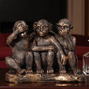 Op de afbeelding: Een bronzen sculptuur die de drie wijze apen uitbeeldt: Zie geen kwaad, hoor geen kwaad, spreek geen kwaad. De apen zitten samen op een voetstuk, waarbij de ene zijn ogen bedekt, de andere zijn oren en de derde zijn mond.