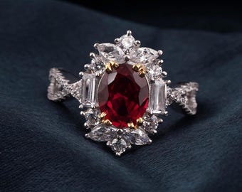 Può includere: Anello in argento con un grande rubino centrale ovale, circondato da pietre bianche e baguette più piccole. L'anello presenta un design dettagliato e ornato con un accento dorato attorno al rubino.
