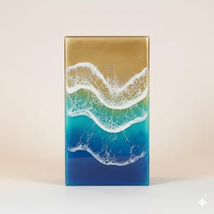 Puede incluir: Obra de arte rectangular de resina que representa una escena de playa. La parte superior es dorada, pasando a olas blancas y espumosas sobre aguas turquesas y azul oscuro. La obra está enmarcada en dorado.