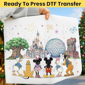 May include: A white DTF transfer sheet featuring a colorful illustration of Disney characters and landmarks, including Cinderella's castle, Spaceship Earth, and the Tower of Terror. The text "Ready To Press DTF Transfer" is at the top.