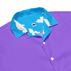 May include: A purple button-down shirt with a blue collar featuring a white cloud pattern. The shirt has white buttons and a small black and white logo on the collar.