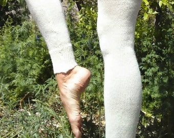 May include: A pair of white knitted leg warmers, worn on a person's legs. The leg warmers are made of a soft, fluffy material and have a ribbed texture.