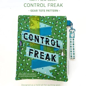 May include: A green quilted fabric tote bag featuring a floral pattern and two blue banners with the text CONTROL FREAK in black letters. The bag includes a blue wrist strap with a white bird icon and a clear plastic ruler tucked into a pocket.