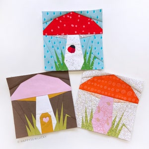 May include: Three fabric mushroom applique patterns with different designs and colours. The first mushroom is red with white spots and a blue background with raindrops. The second mushroom is pink with a brown background and green grass. The third mushroom is orange with a white background and green grass.