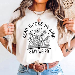 A woman wearing a white t-shirt with a graphic design and text printed on it.