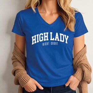 A woman wearing a blue t-shirt with the text "HIGH LADY NIGHT COURT" printed on it.