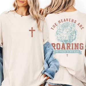 two women wearing white t-shirts with a graphic design on the back.