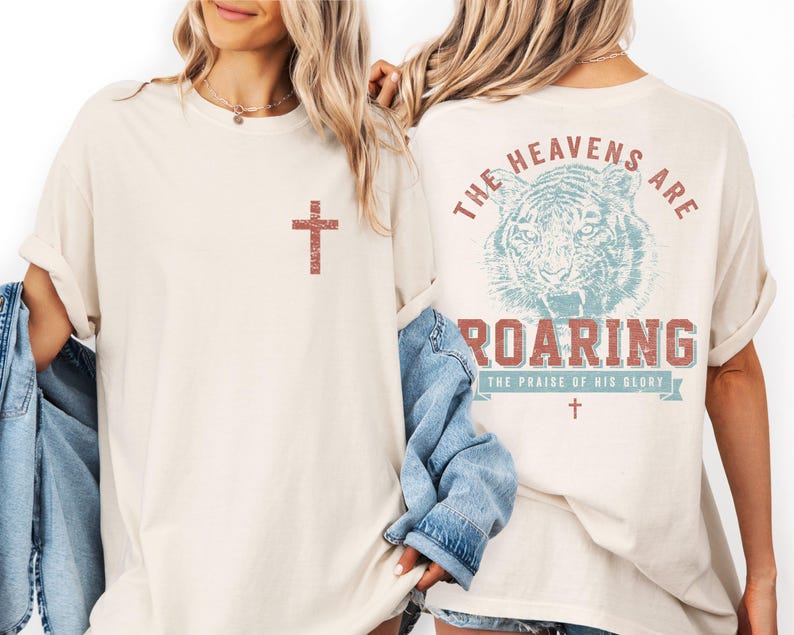 two women wearing white t-shirts with a graphic design on the back.