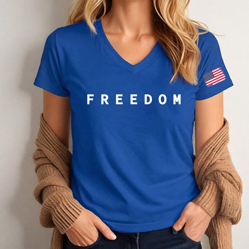 A woman wearing a blue t-shirt with the word "FREEDOM" printed on it, standing against a white background.