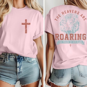 The image is a collage of two photos of a woman wearing a pink t-shirt with a cross and the text "The heavens are roaring" printed on it.