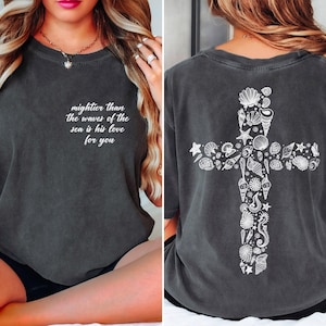 The image is a collage of two photos. In the first photo, a woman is sitting on a bed with her legs crossed, wearing a gray t-shirt with a cross design and text on the back. In the second photo, the woman is sitting on the bed, wearing the same gray t-shirt with the same cross design and text on the back.