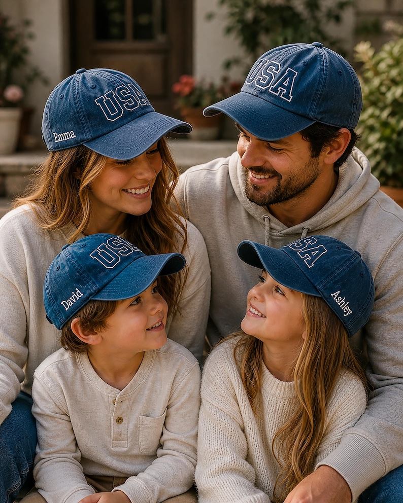 A family of four, consisting of a mother, father, and two children, are sitting together and smiling. They are all wearing matching blue hats with the word "USA" printed on them.
