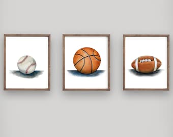 May include: Three framed prints of watercolour illustrations of sports balls. The prints feature a baseball, a basketball, and a football.
