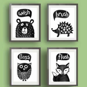 May include: Four black and white framed prints with animal illustrations and bathroom-related words. The prints feature a bear with the word "wash", a hedgehog with the word "brush", an owl with the word "floss", and a fox with the word "flush".