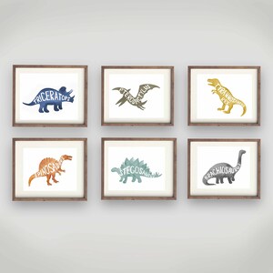 May include: Six framed watercolor dinosaur prints with the dinosaur's name written inside the silhouette. The prints are in a variety of colors, including blue, green, orange, and yellow.