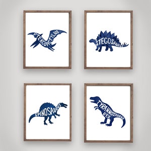 Może przedstawiać: Zestaw czterech niebieskich akwarelowych wydruk&oacute;w sylwetki dinozaur&oacute;w z nazwami dinozaur&oacute;w wypisanymi w sylwetce. Wydruki są oprawione w brązowe drewniane ramki.