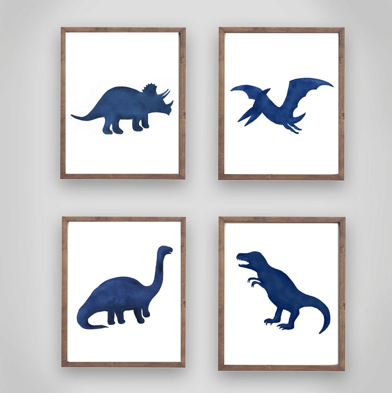Może przedstawiać: Zestaw czterech oprawionych wydruk&oacute;w przedstawiających sylwetki dinozaur&oacute;w w niebieskiej akwareli. Wydruki obejmują triceratopsa, pterodaktyla, brachiozaura i tyranozaura.