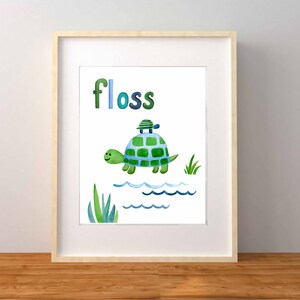May include: A framed print with a watercolor illustration of two green turtles swimming in blue water. The word "floss" is written in blue and green letters above the turtles.