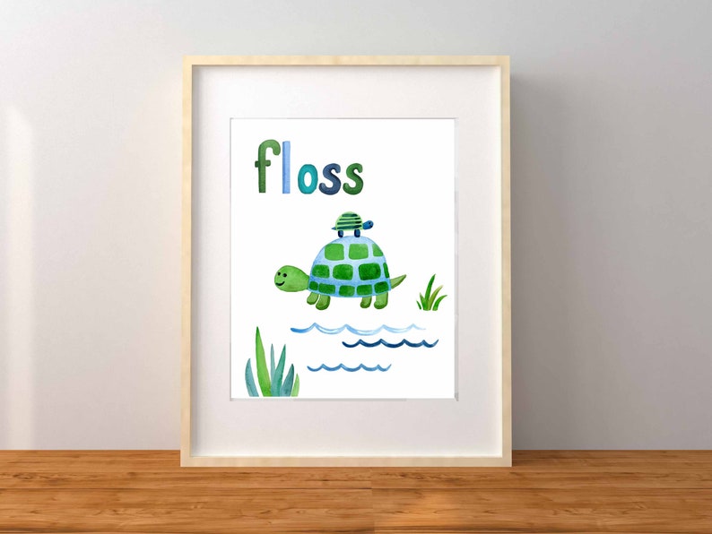 May include: A framed print with a watercolor illustration of two green turtles swimming in blue water. The word "floss" is written in blue and green letters above the turtles.