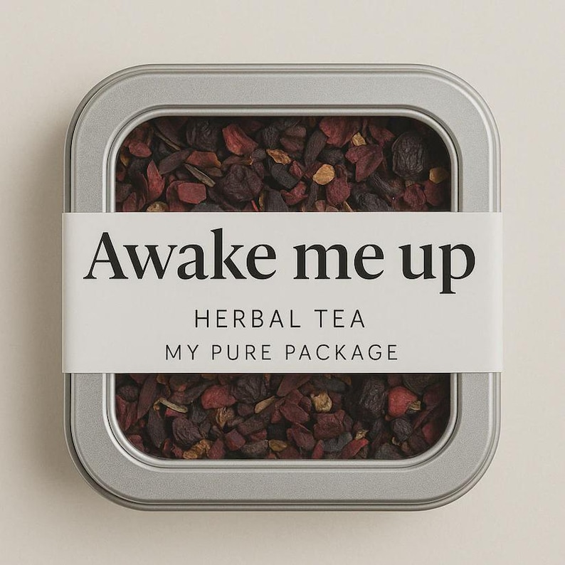 May include: A rectangular, silver-colored tin filled with loose-leaf herbal tea. A white label wraps around the tin, displaying the text "Awake me up" in a bold, black font. Below, the label reads "HERBAL TEA" and "MY PURE PACKAGE". The tea leaves are a mix of dark red and brown.