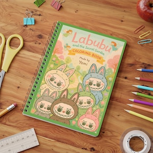May include: A spiral-bound coloring book titled "Labubu and the Secret Garden" with a green cover featuring cartoon bunny characters. The book is surrounded by colored pencils, a ruler, and other stationery items on a wooden surface.